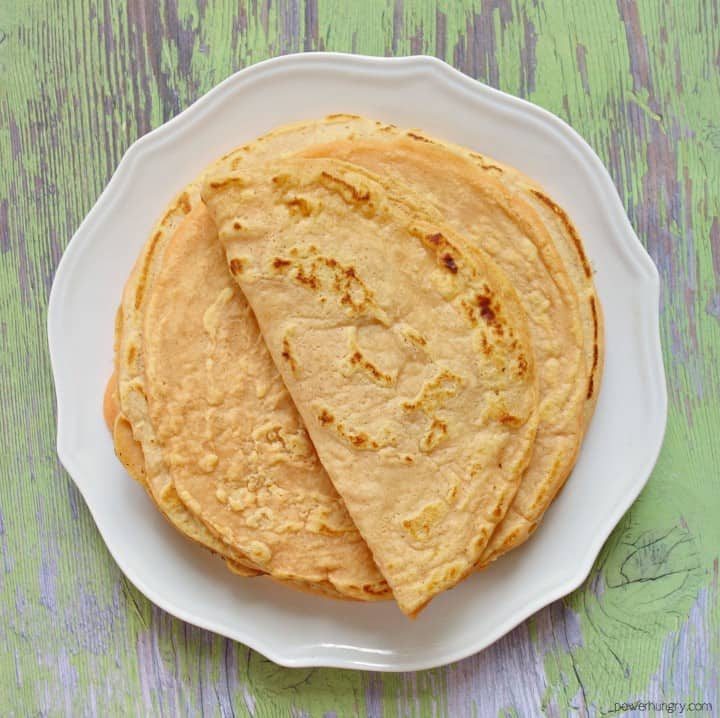 stack of 1-ingredient red lentil tortillas on a white plate, top tortilla folded