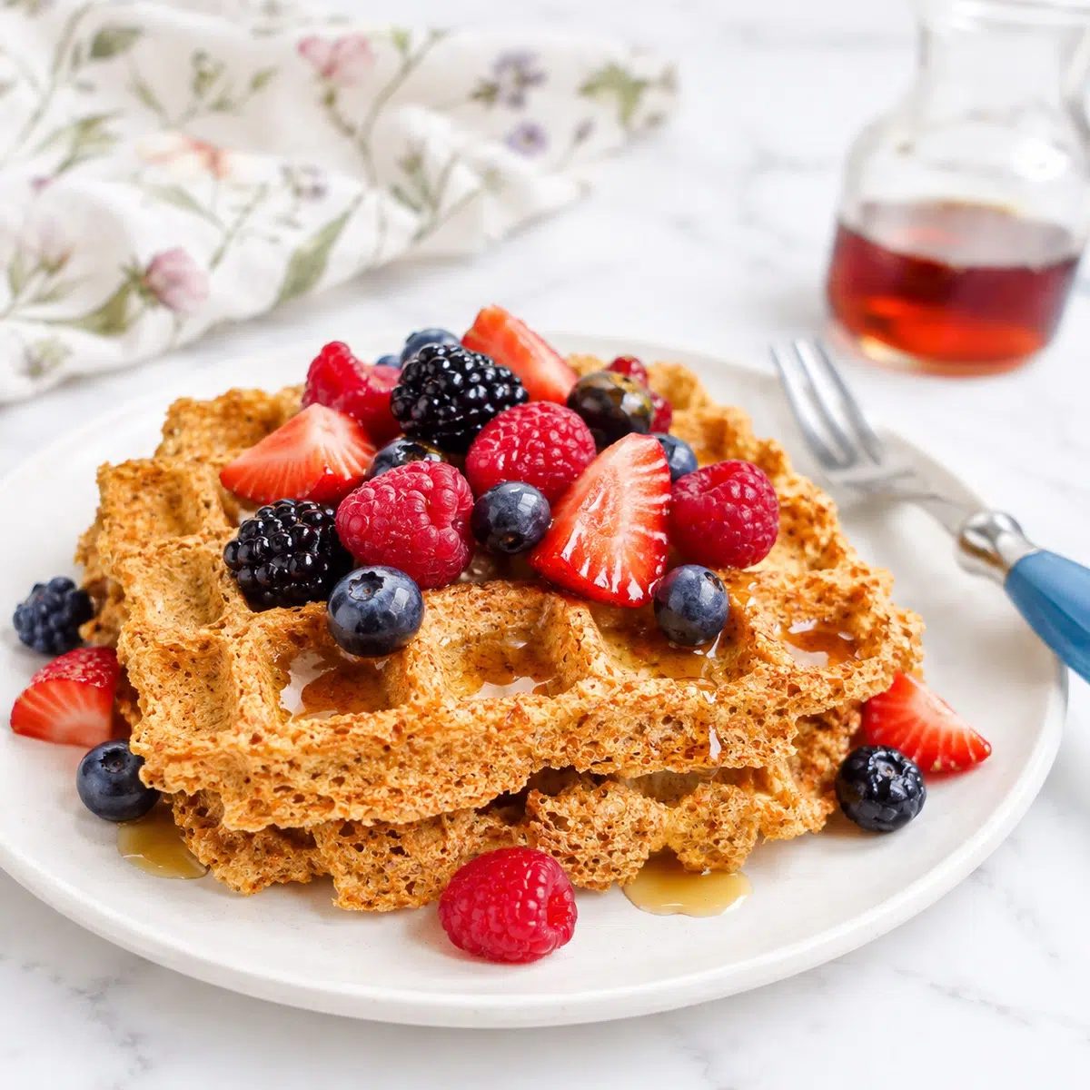 flaxseed waffles plated with berries and maple syrup