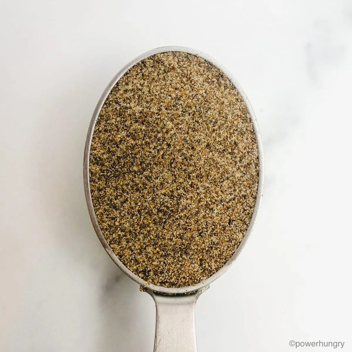 a lightly packed silver measuring cup filled with chia seed flour.