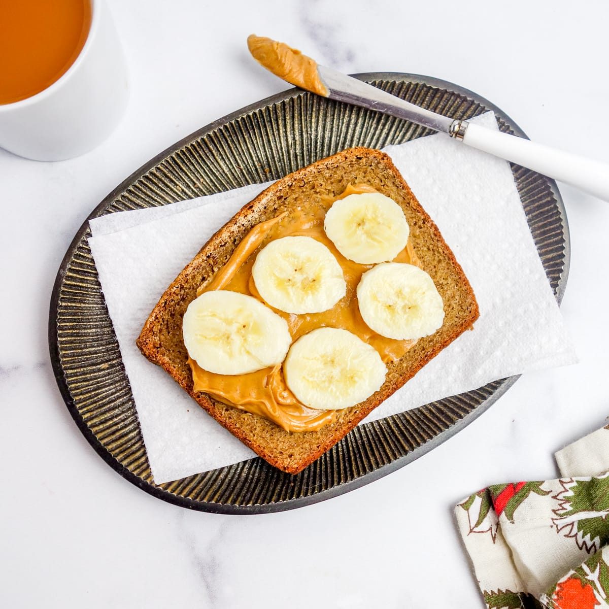overhead shot of a slice of banana bread topped with peanut butter and sliced bananas