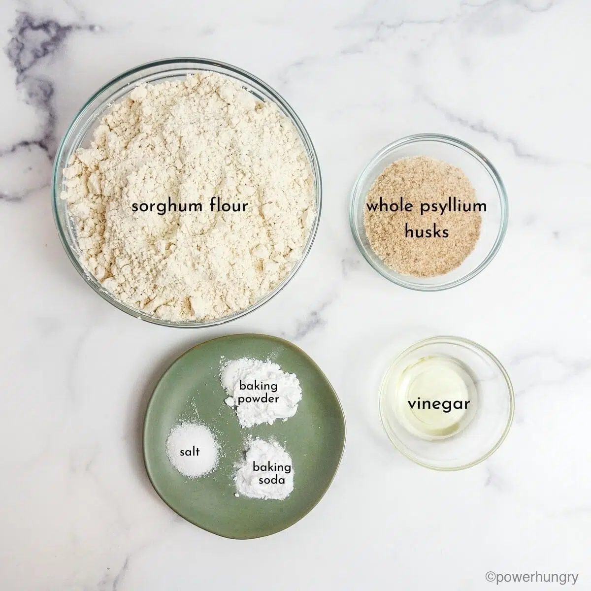 sorghum flour bread ingredients in small bowls on a white marble background