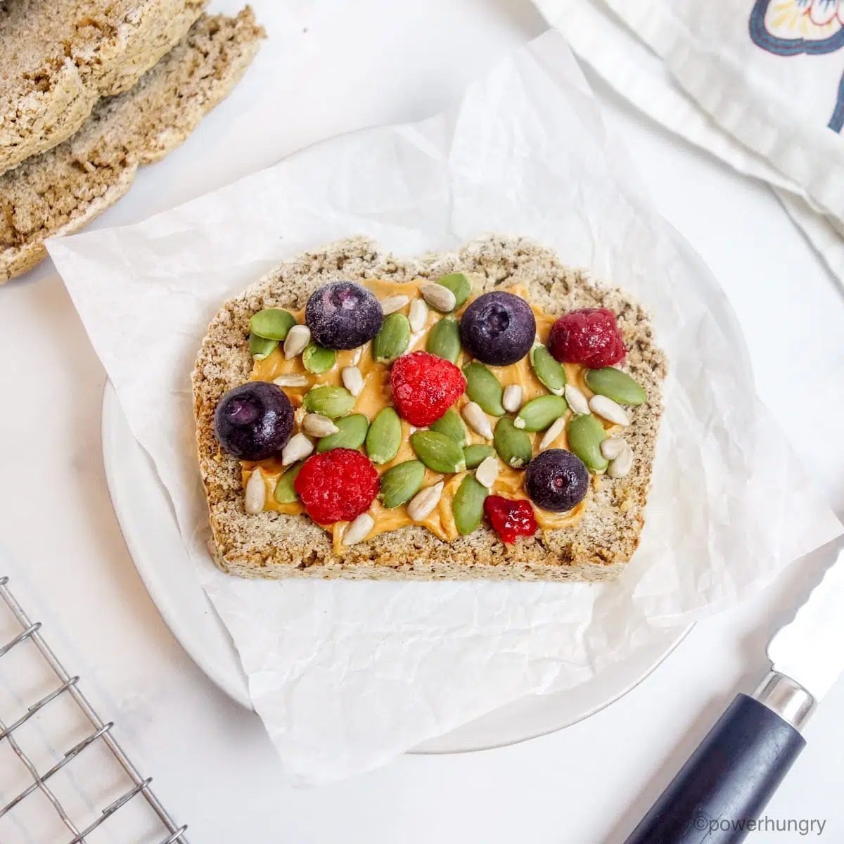 a slice of gluten-free bread topped with sunflower seed butter, seeds, and berries