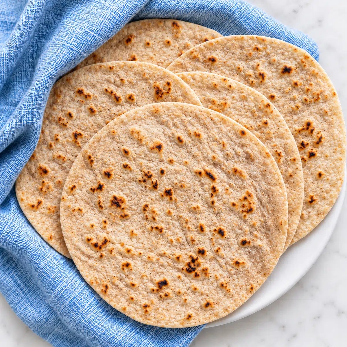 cassava flour tortillas on white plate with blue napkin