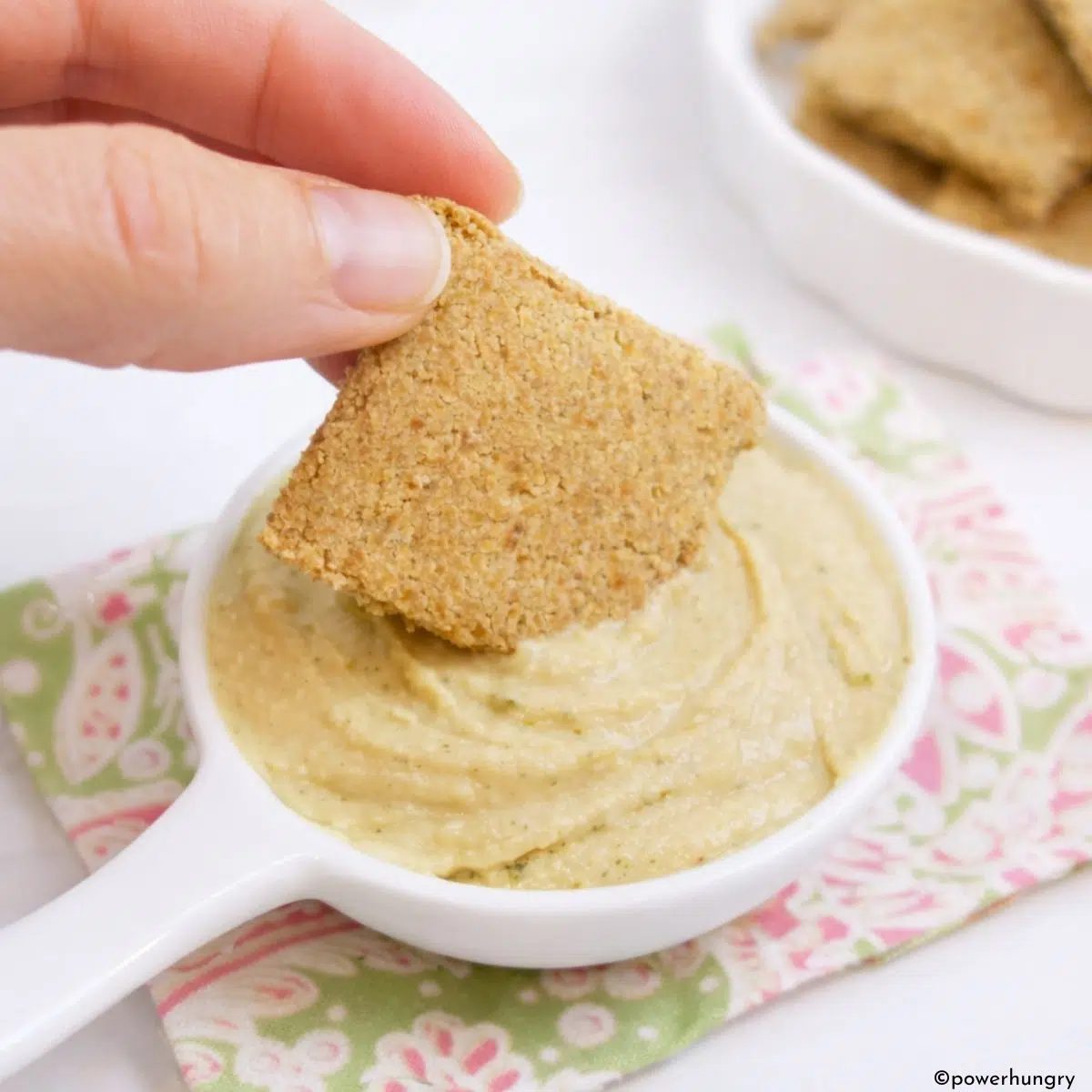 2-Ingredient Chickpea Flour Crackers getting dipped into hummus.