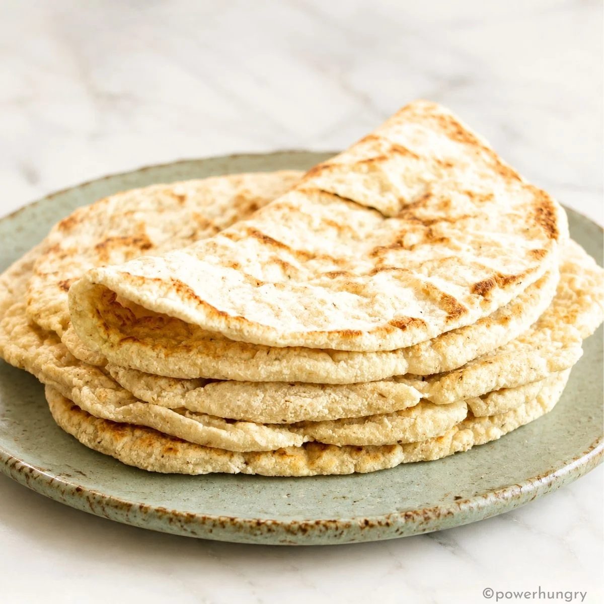 stack of 2 ingredient coconut flour tortillas on a green stoneware plate