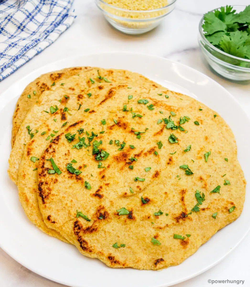 stack of millet naan on a white plate with chopped cilantro on top