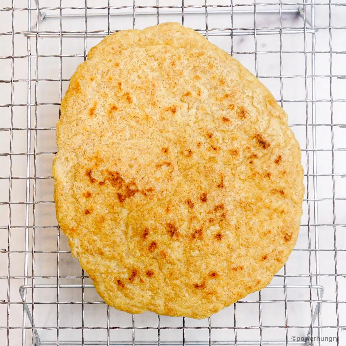 a piece of millet naan on a silver wire cooling rack