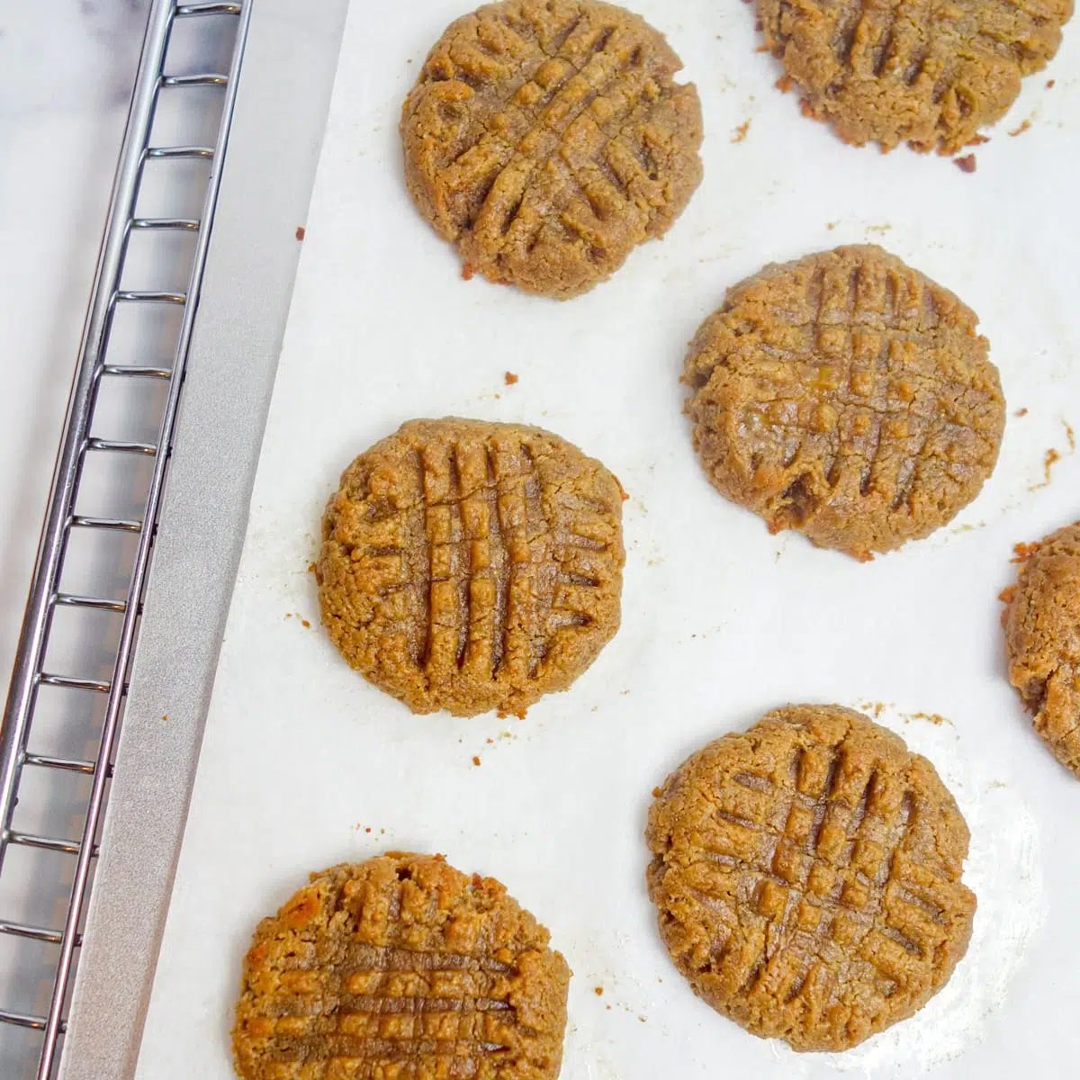 baked peanut butter banana cookies on a baking sheet atop a cooling rack.