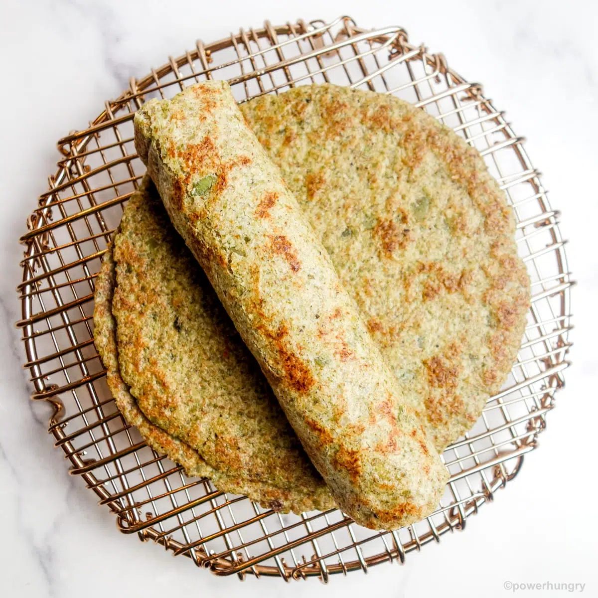 a stack of pepita tortillas, with one rolled one on top