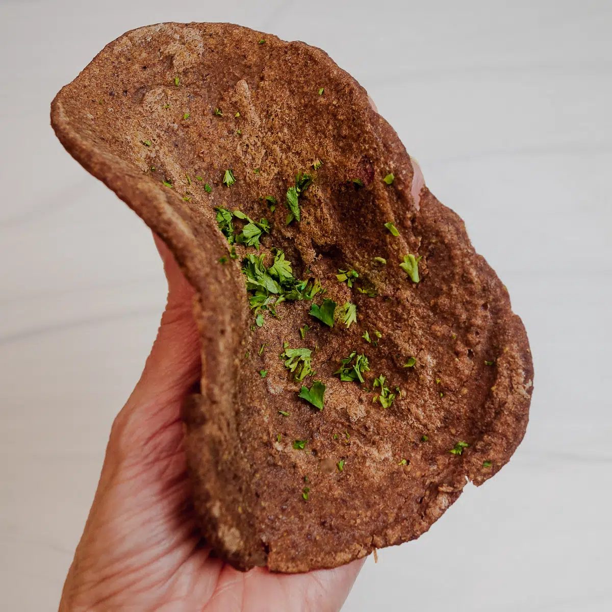 2 ingredient teff naan being bent with a hand