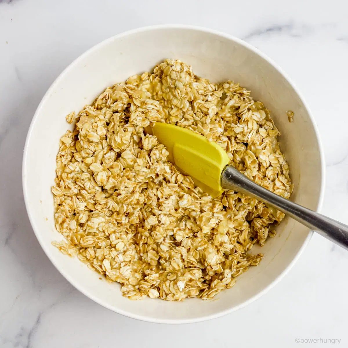 a white mixing bowl filled with a banana oat dough