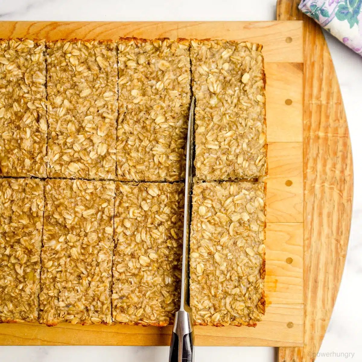 banana bars on a wood cutting board being cut into bars