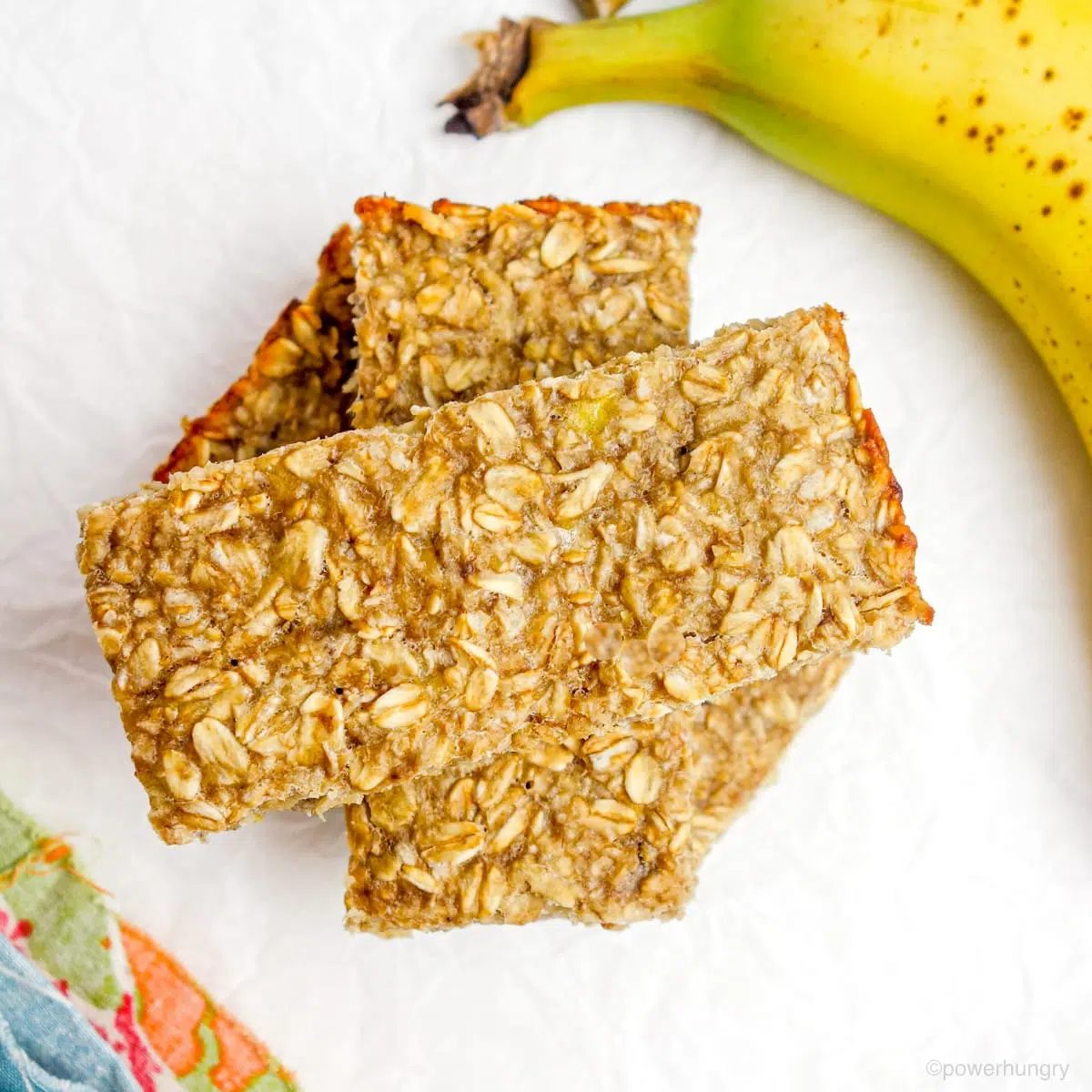 a stack of 3 banana oat bars on white parchment paper.