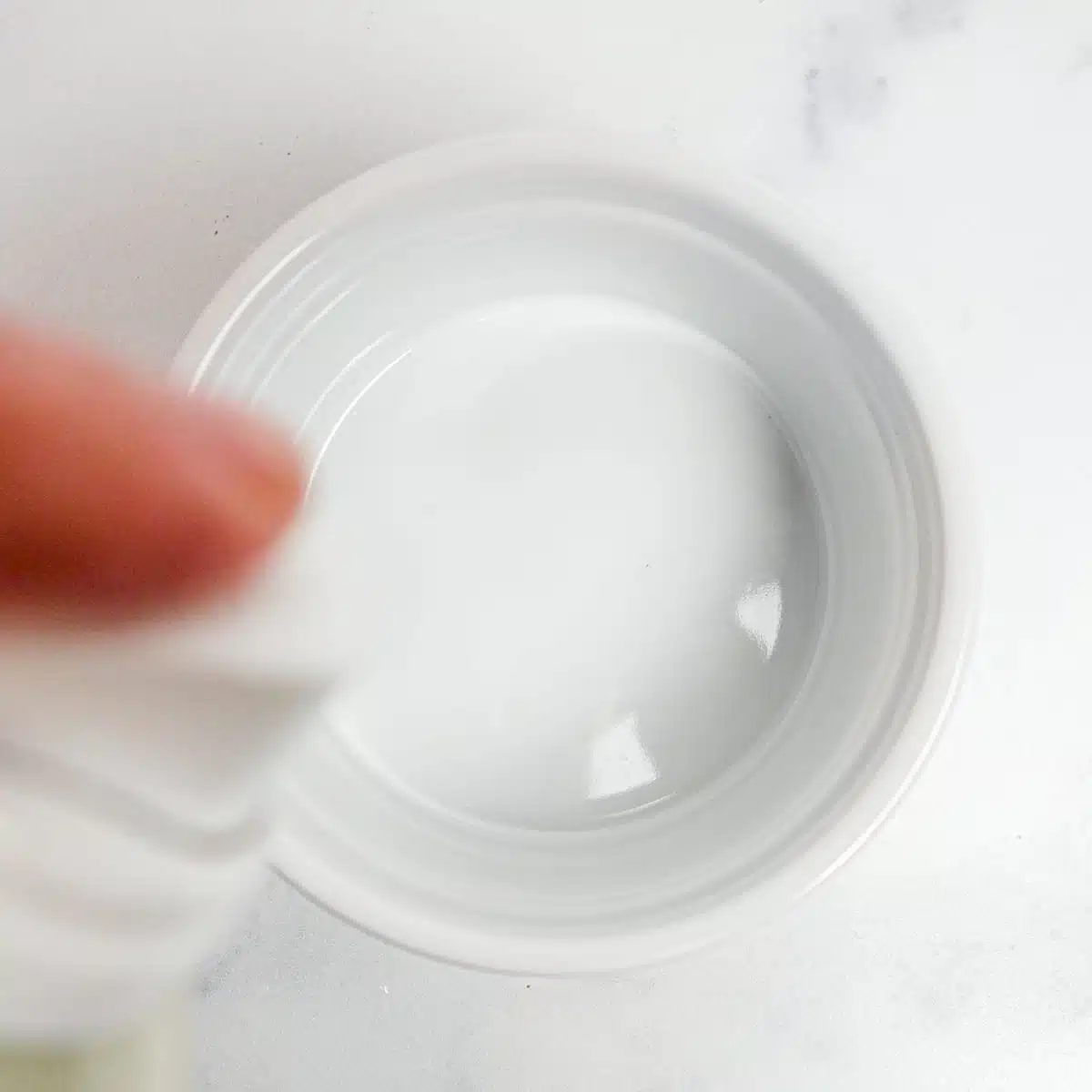 white ramekin being sprayed with nonstick cooking spray