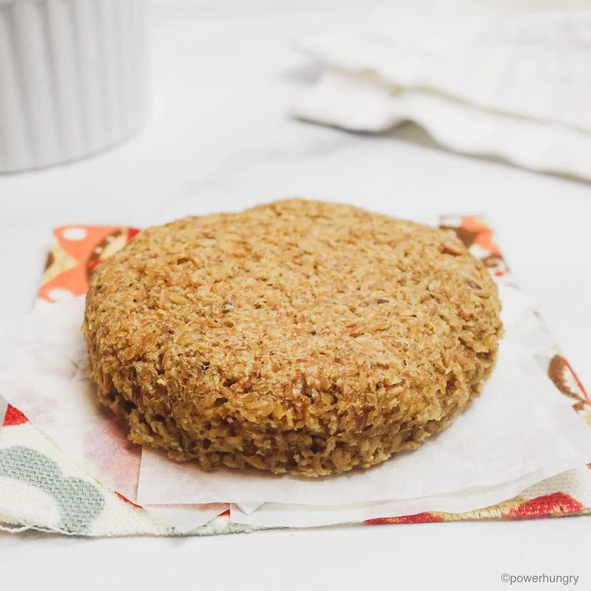 a piece of microwave flax bread , on white parchment paper, atop a floral napkin
