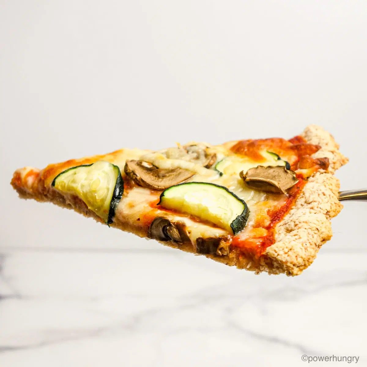 single slice of almond flour pizza crust in front of a white background