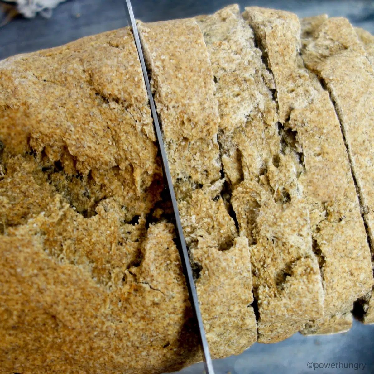 millet chia bread getting sliced on a grey cutting board
