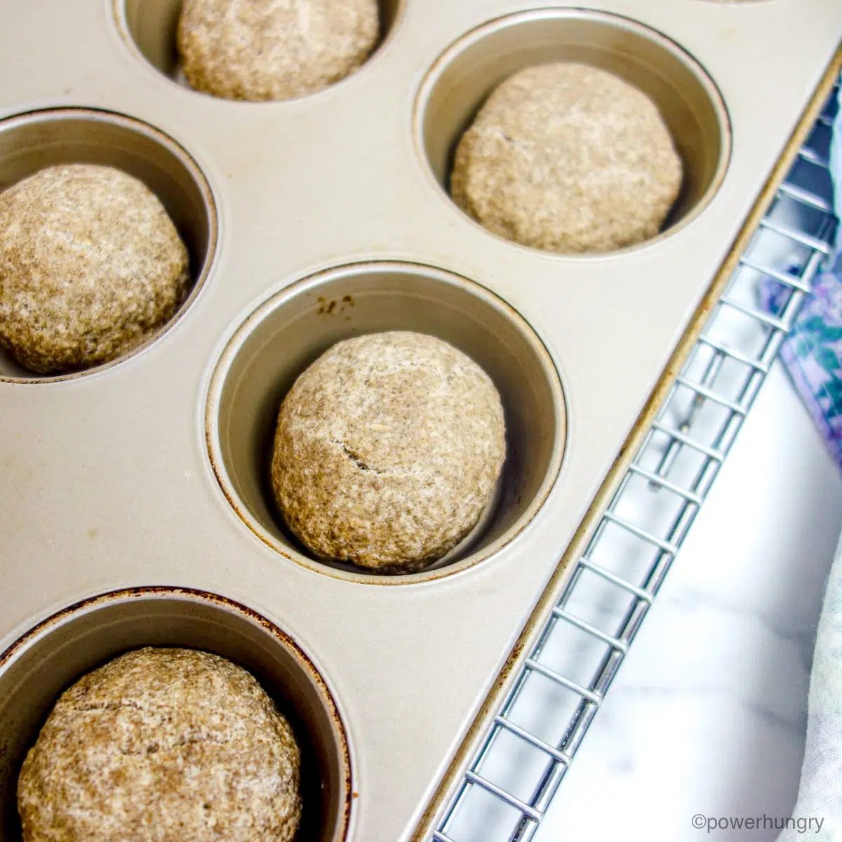 baked nourishing rolls in a muffin tin on top of a cooling rack.
