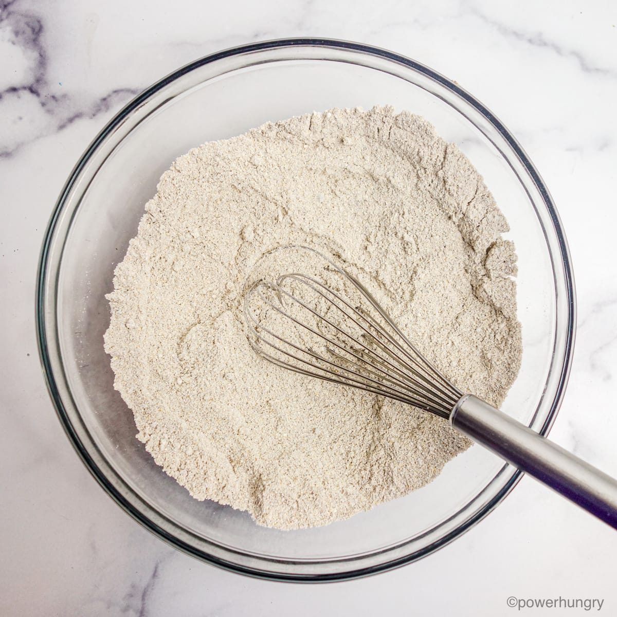 a clear glass bowl filled with dry ingredients for chia oat rolls.