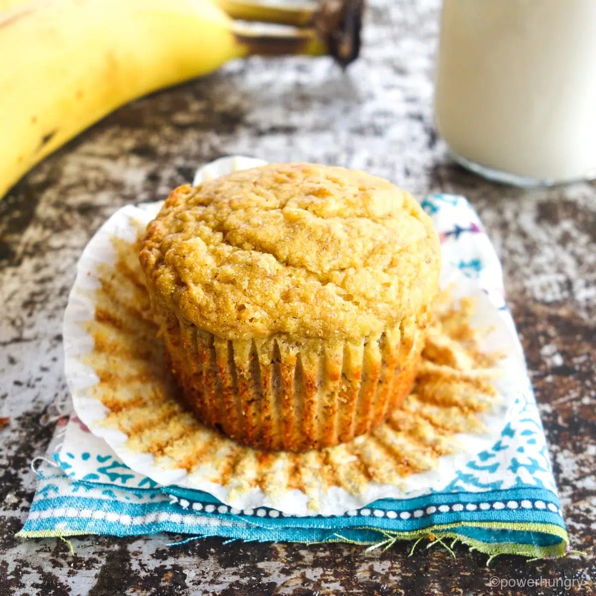 a single vegan banana muffin, unwrapped from its paper wrapper, and sitting on a colorful napkin