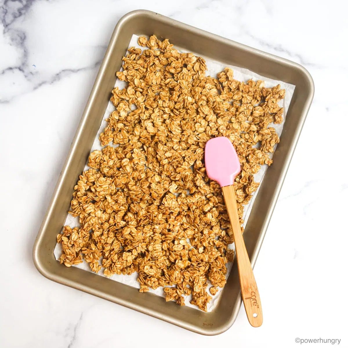 granola tamped down with a pink spatula