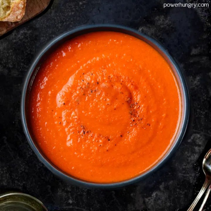 overhead shot of 3-ingredient tomato lentil soup in a dark bowl on top of a slate board