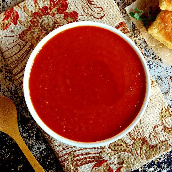 overhead shot of vegan tomato soup on a floral, fall napkin