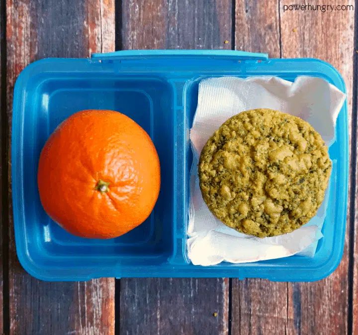 blue bento box filled with a mandarin orange and a vegan pesto chickpea flour muffin
