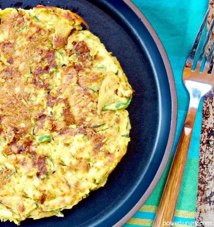 overhead close-up of zucchini chickpea flour omelet (soccata) with a turquoise napkin alongside