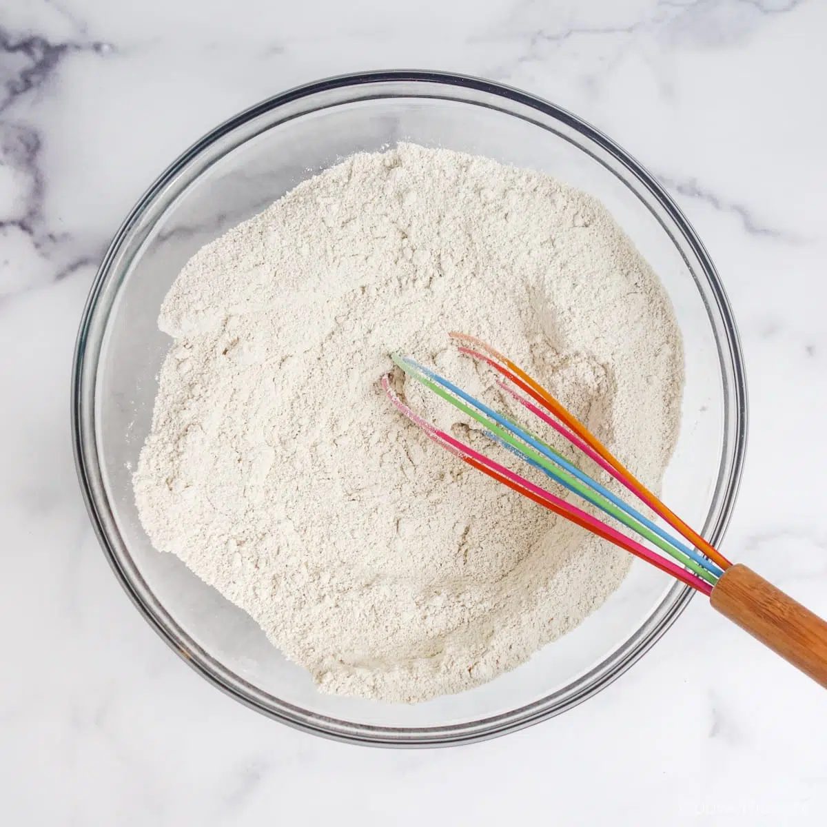 large glass bowl filled with whisked oat flour and baking soda