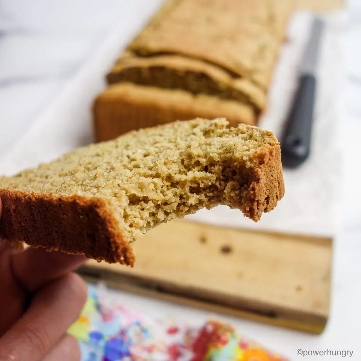 a slice of oat bread, held in one hand, with a bite taken out of the slice