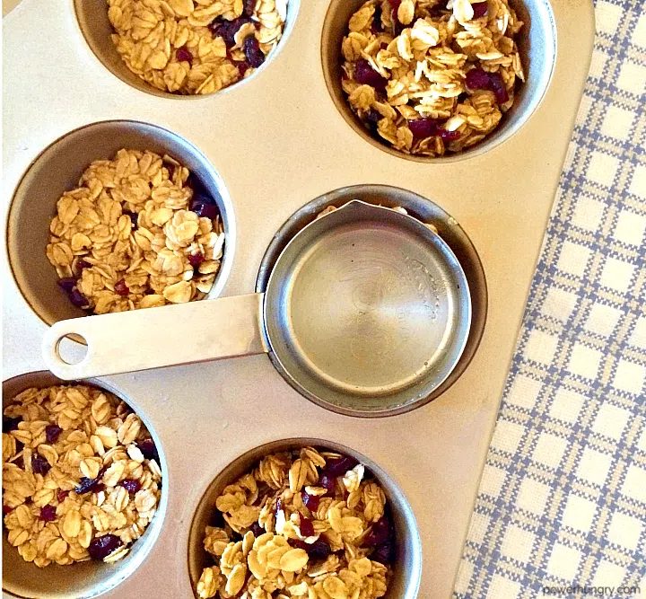 muffin tin granola bars getting tamped down in tin