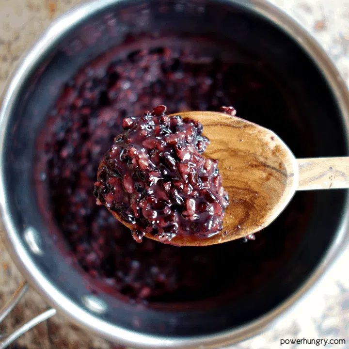 close up of cooked black rice on a wooden spoon