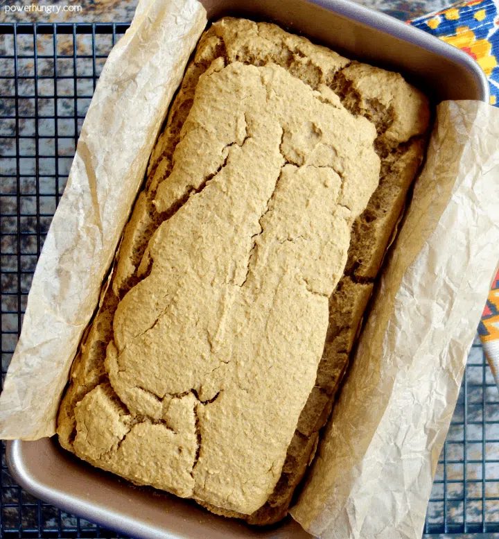 baked loaf of lentil bread in pan on a cooling rack