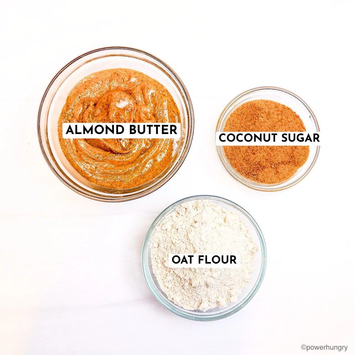 almond butter oat flour cookies ingredients in glass bowls on marble surface
