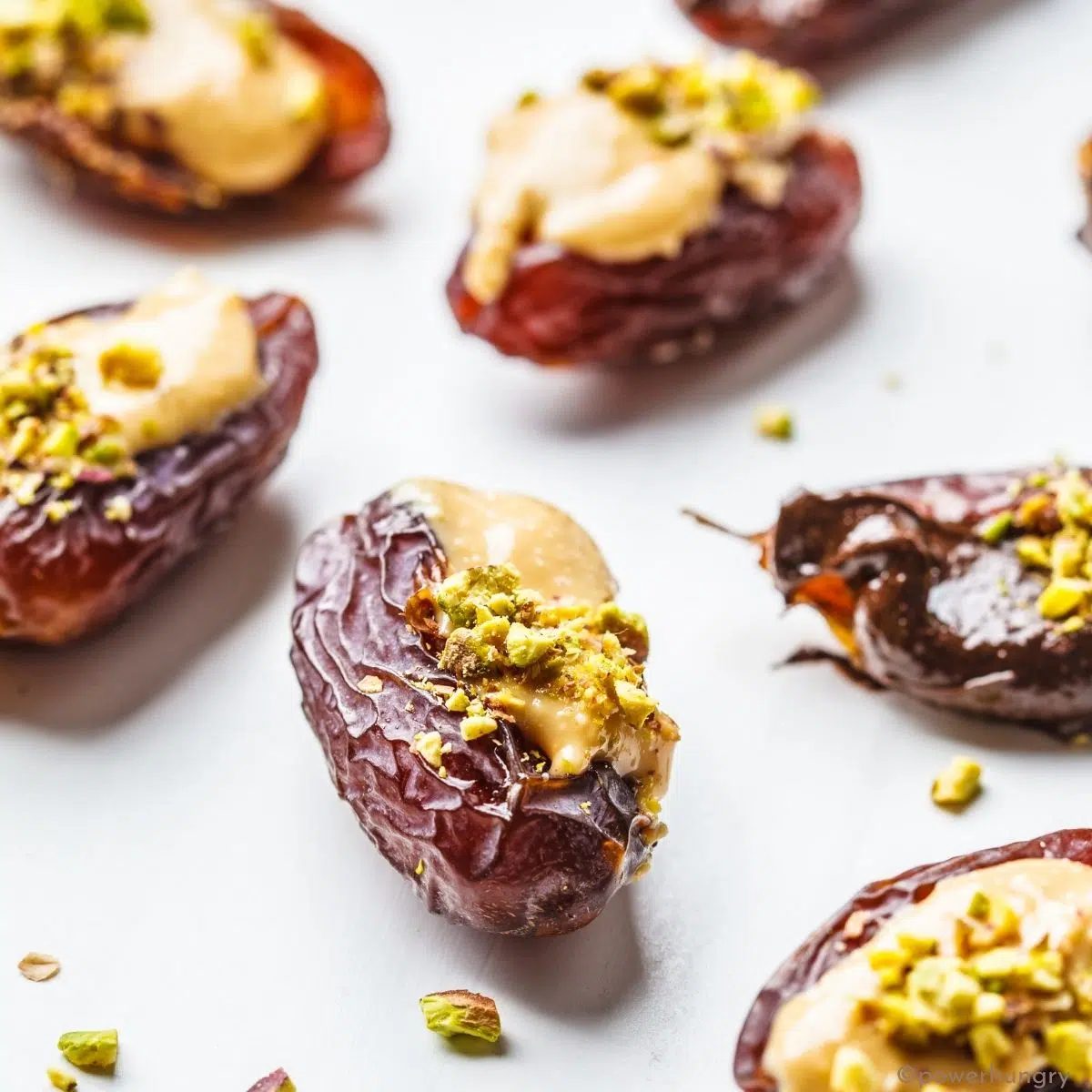 almond butter stuffed dates on a white surface