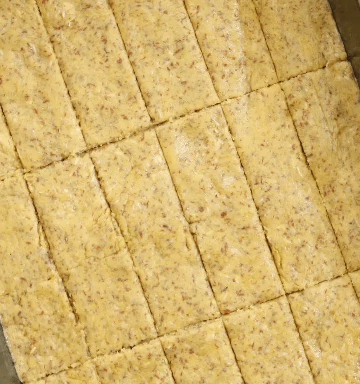 unbaked almond oat & chickpea flour crackers cut into pieces and ready to be baked on a baking sheet