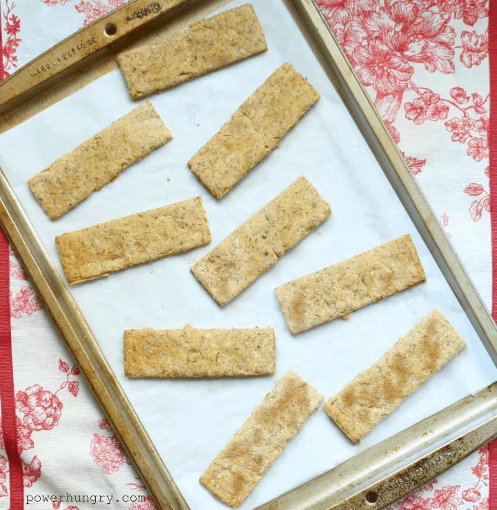 Almond, oat & chickpea flour crackers on a parchment paper-lined baking sheet