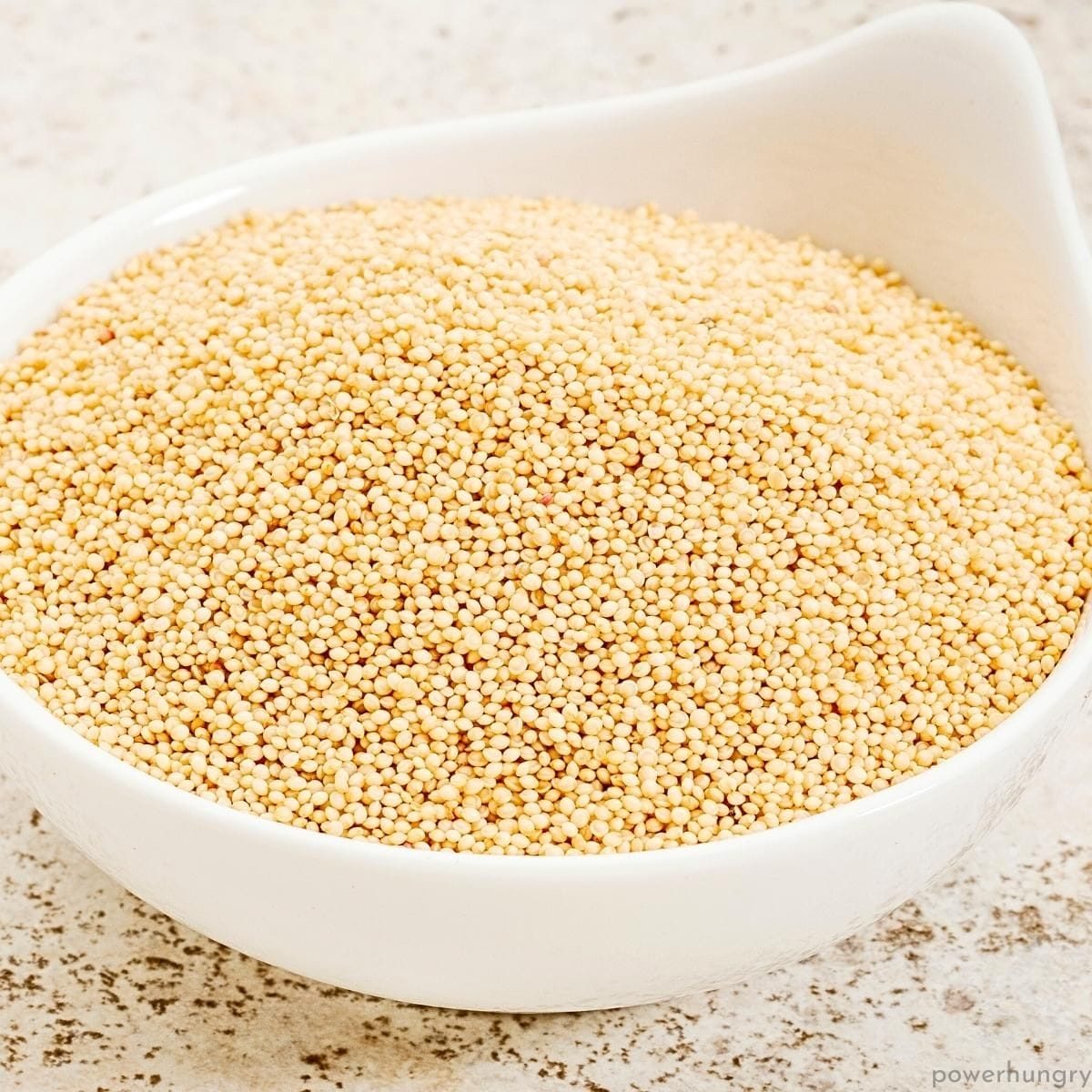 a small white bowl filled with uncooked amaranth grains