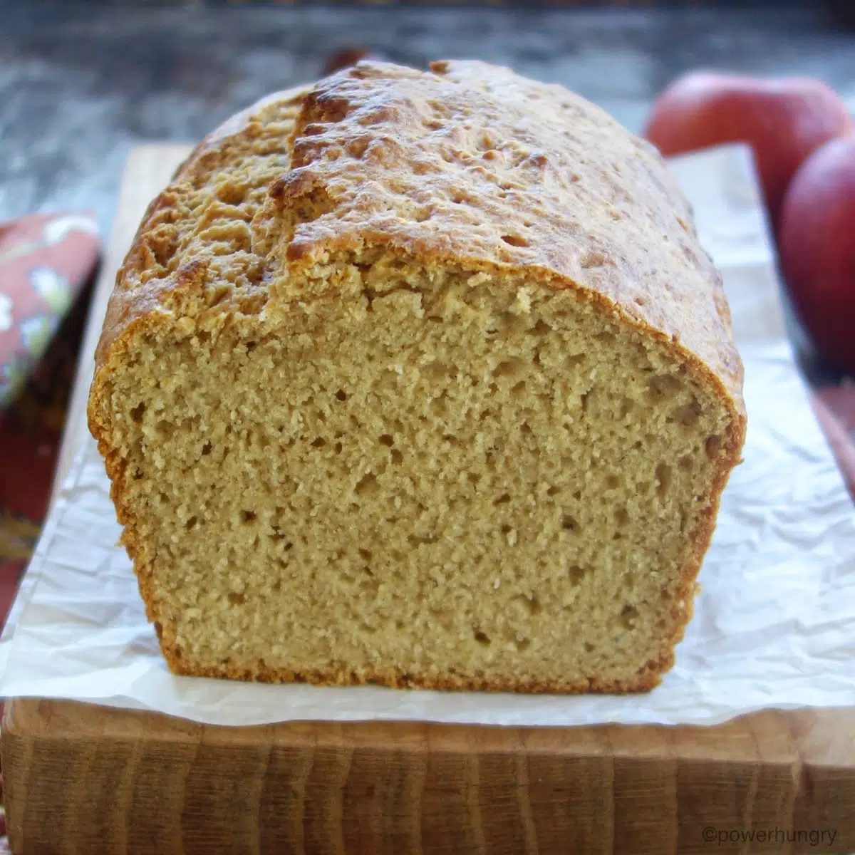 close up of sliced end of a loaf of applesauce millet bread on a wood cutting board