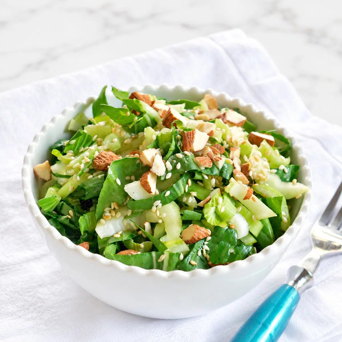 angled view of white bowl filled with baby bok choy salad