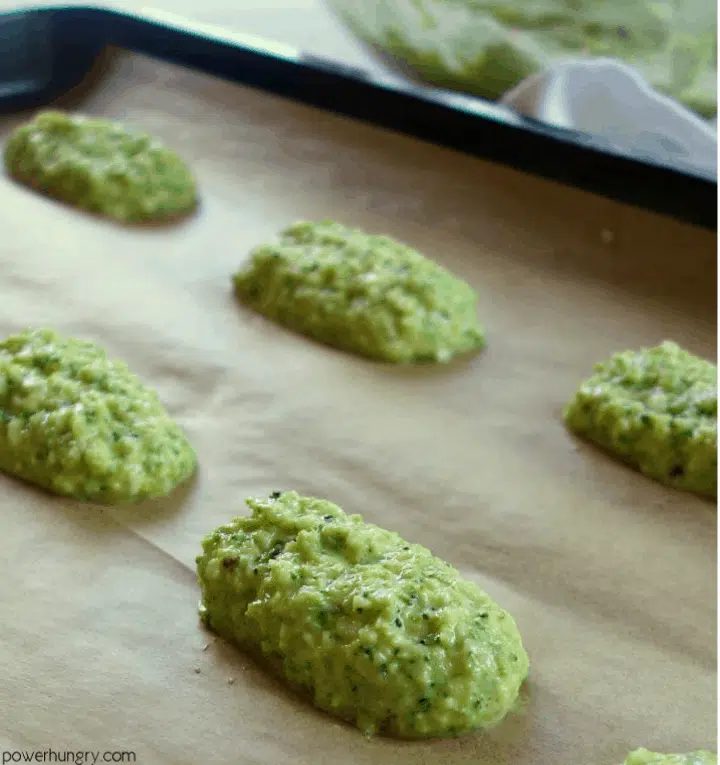 portions of chickpea flour broccoli tot dough on a parchment paper lined baking sheet
