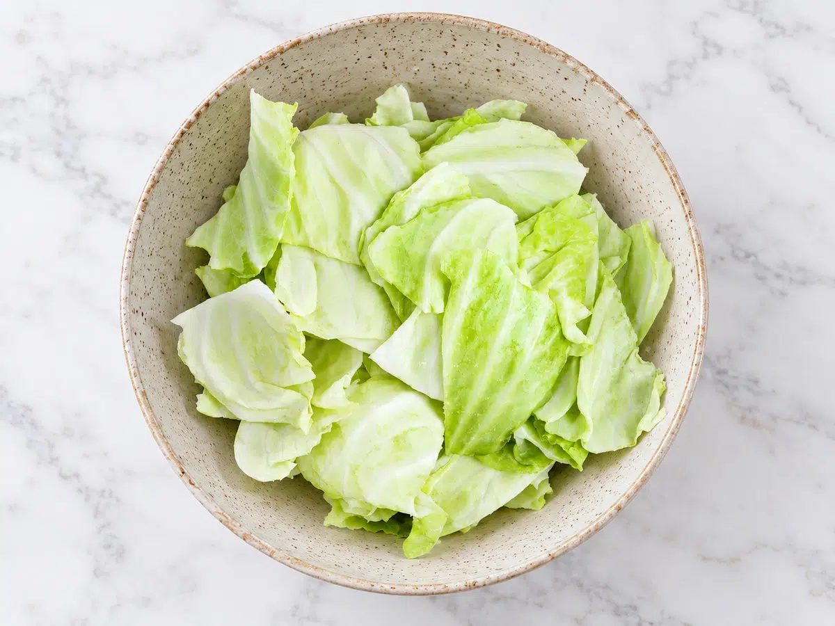 cabbage leaves getting tossed with oil and salt in a bowl for crispy cabbage chips