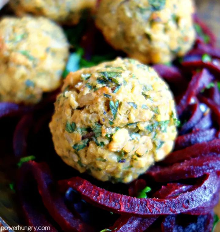 close of of vegan meatballs atop beet noodles