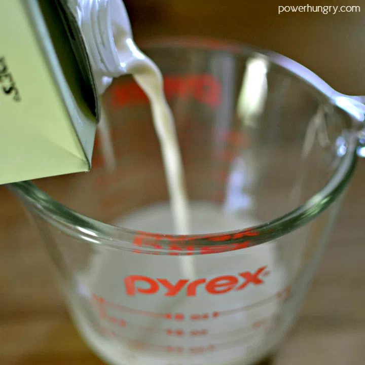 overhead shot of nondairy milk being poured into a glass measuring cup