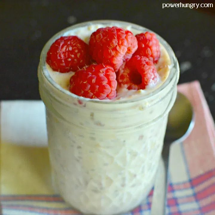 a jar full of banana chia overnight oats, filled to the brim and topped with fresh raspberries