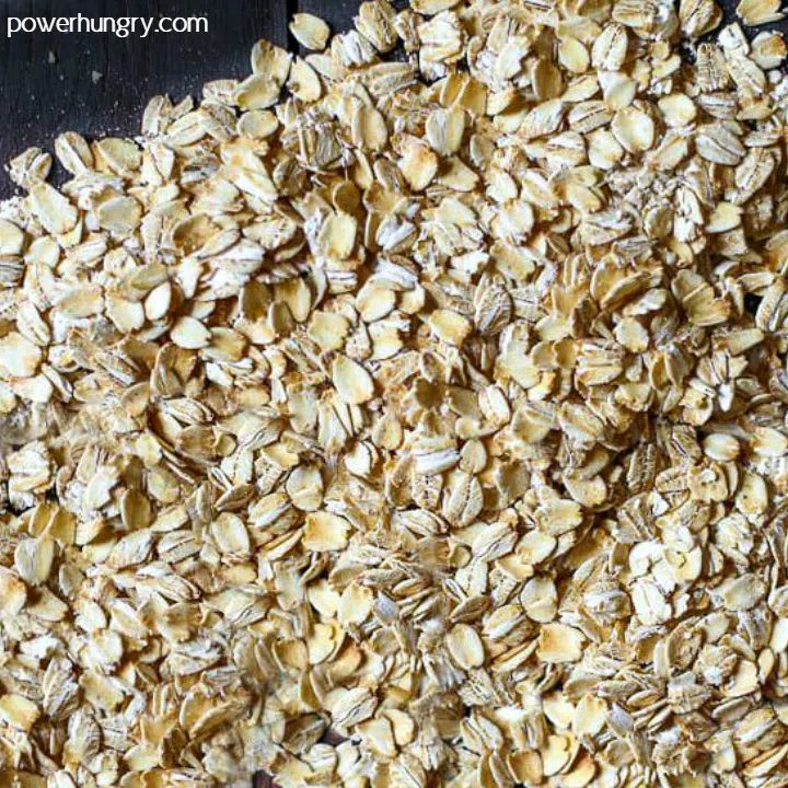 old-fashioned rolled oats spread out on a black cutting board