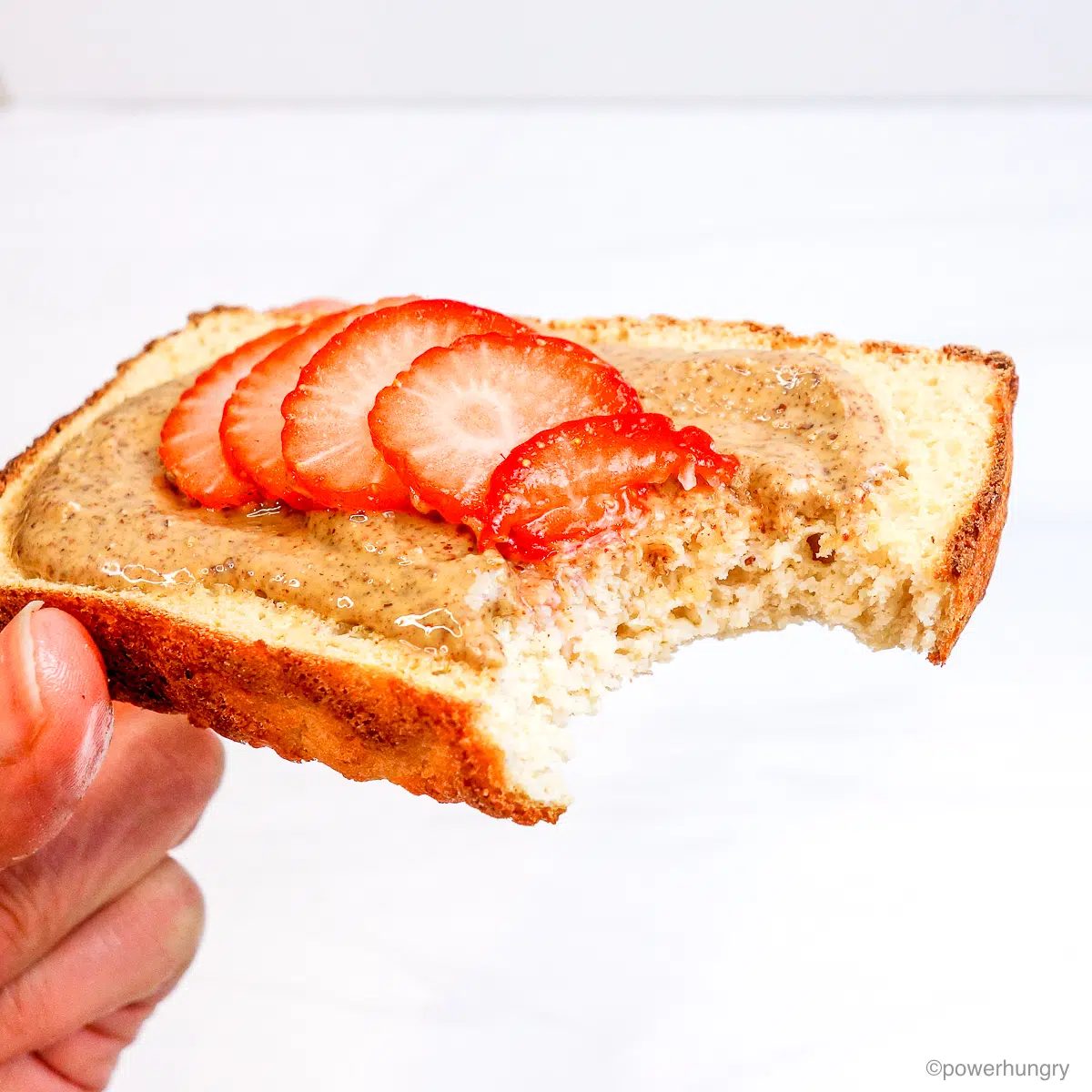slice of millet white ben bread topped with almond butter and strawberries