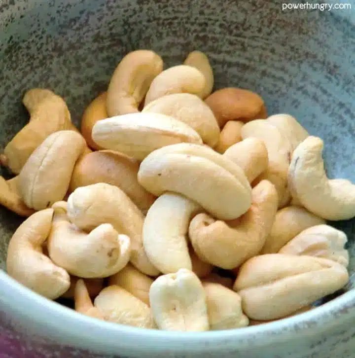 blue stoneware bowl filled with raw cashews