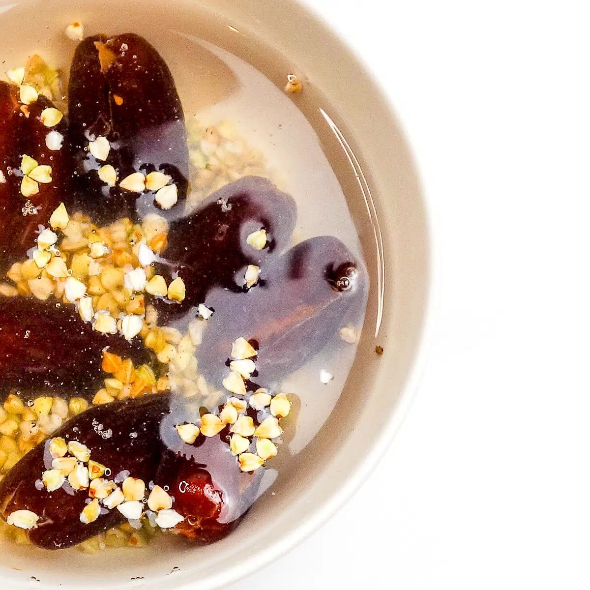 buckwheat groats and dates soaking in boiling water in a white bowl